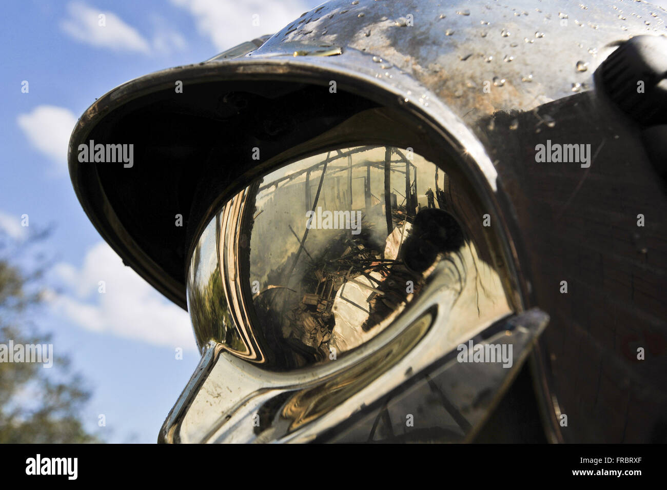 Detail of reflection of the wreckage of house burning in fireman`s helmet Stock Photo